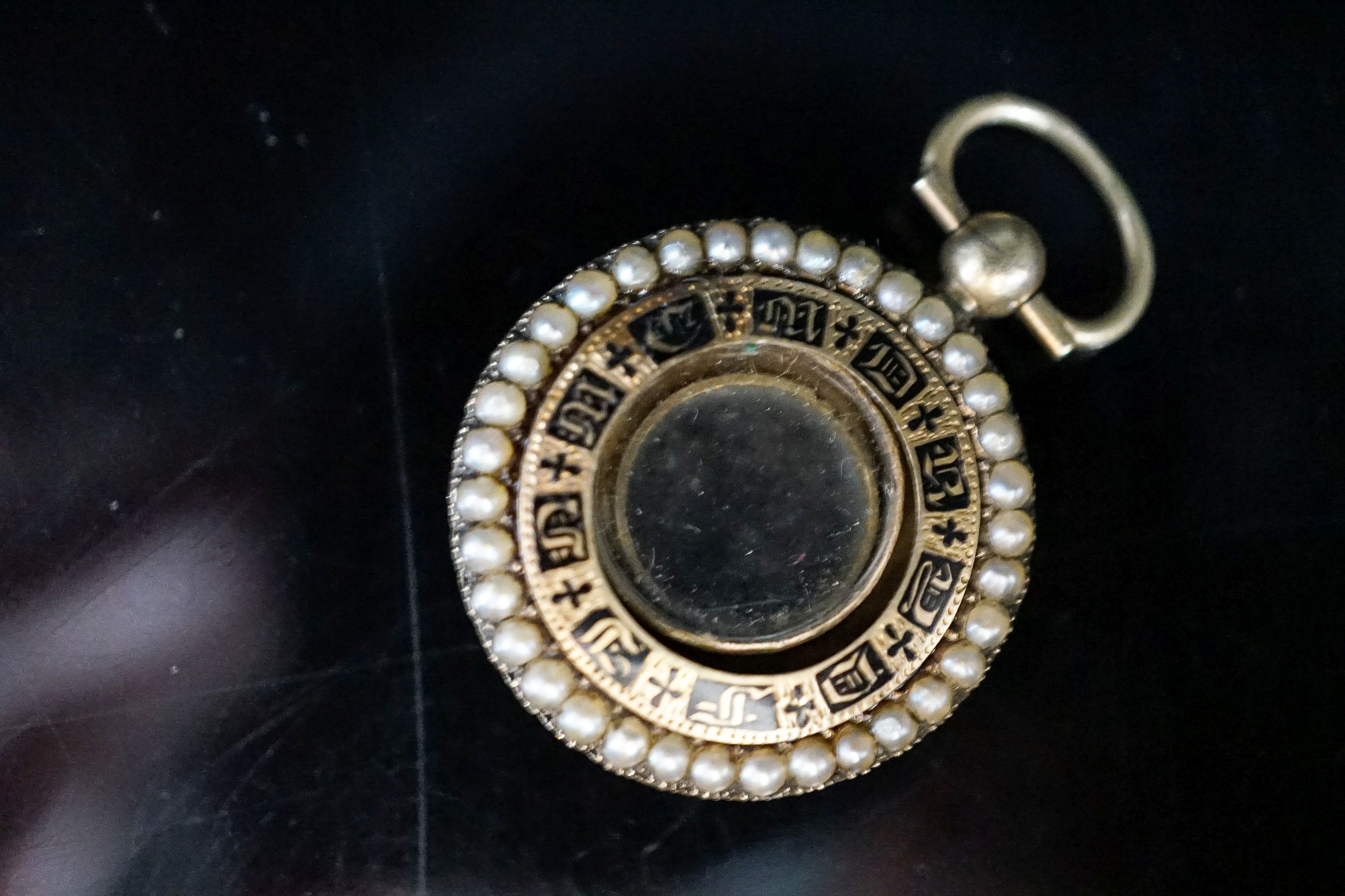 A William IV yellow metal, black enamel and split pearl mounted glazed circular mourning pendant vacant enamelled mourning brooch, 25mm. with engraved inscription, gross 6.5 grams.